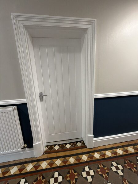 Stand-in photograph of a panelled door in a hallway with patterned floor tiles