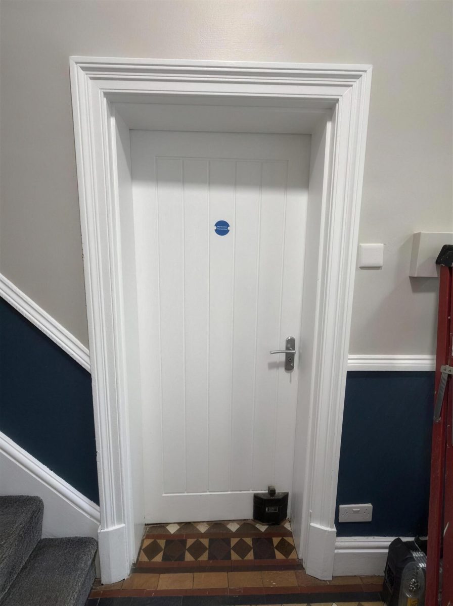 Fire door with an overhead closer in a hallway with a blue dado