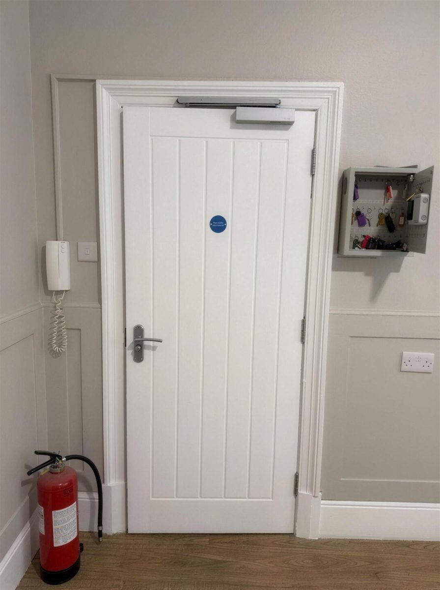 Fire door with an overhead closer beside a fire extinguisher