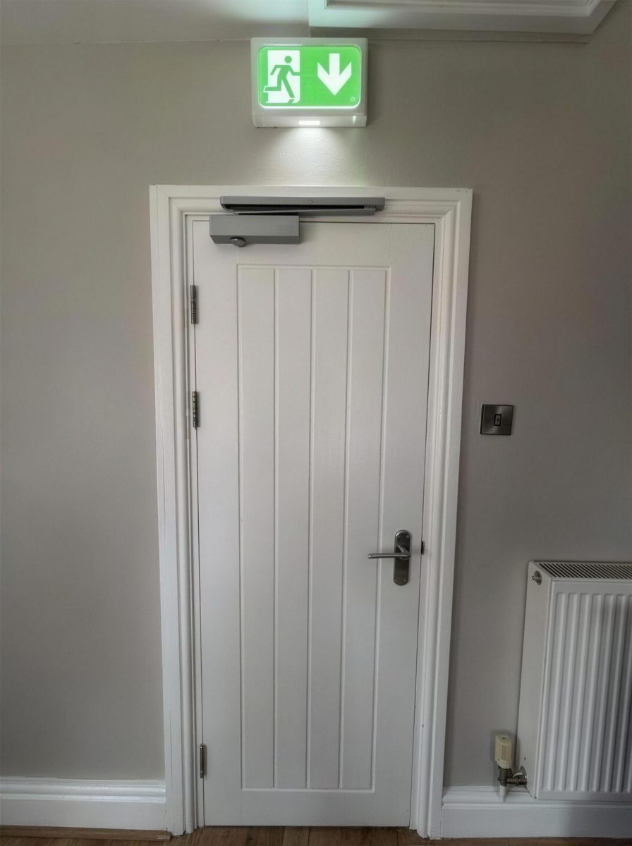 Fire exit door with an overhead closer and an exit sign