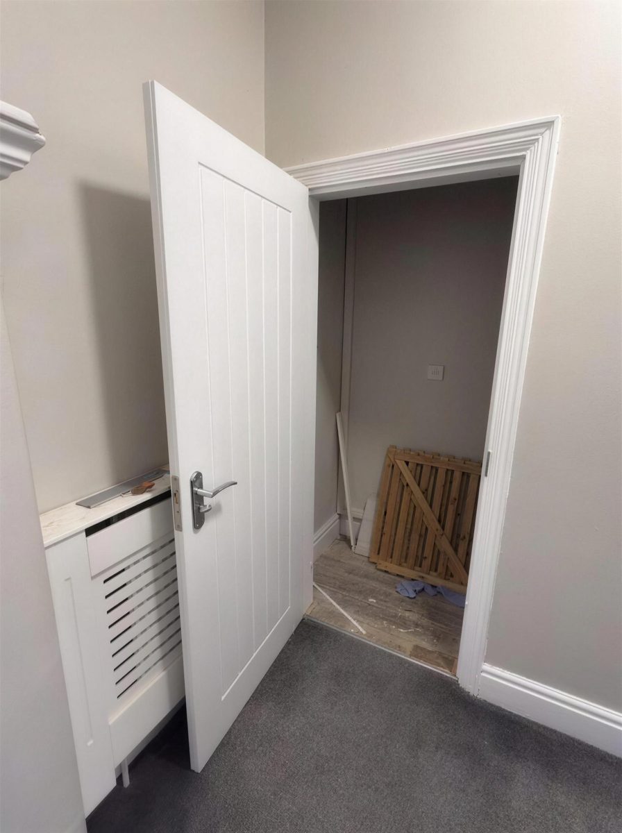Fire door standing open onto a cupboard under the stairs