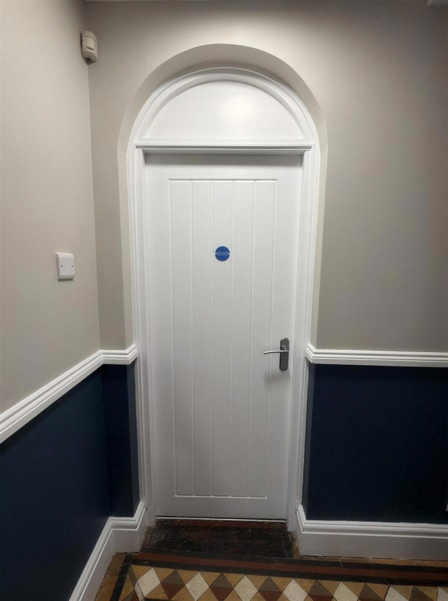 Arched fire door in a hallway with a tiled floor