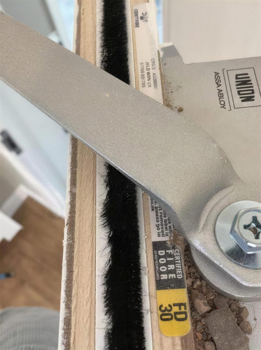 Door closer arm and intumescent strip on a fire door